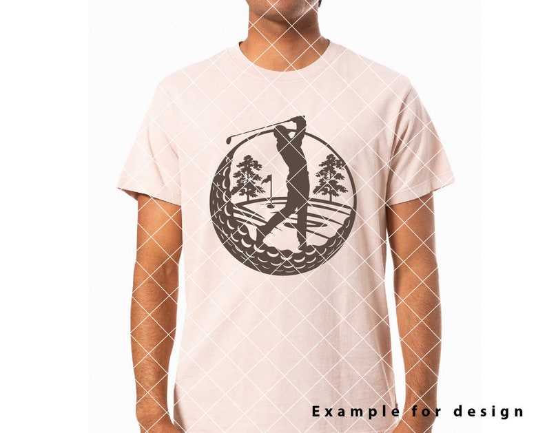 May include: A brown silhouette of a golfer swinging a club on a golf course, surrounded by a circle of golf balls. The design is on a light pink t-shirt.