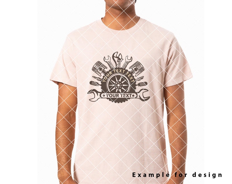 Op de afbeelding: Een lichtroze T-shirt met een bruin grafisch ontwerp van een band met gereedschap en de tekst "YOUR TEXT" twee keer herhaald.