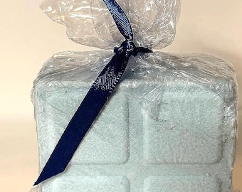 May include: A light blue, square-shaped item, possibly a gift, wrapped in clear cellophane. A dark blue ribbon is tied around the cellophane, securing the package. The item has a textured surface with a grid-like pattern.