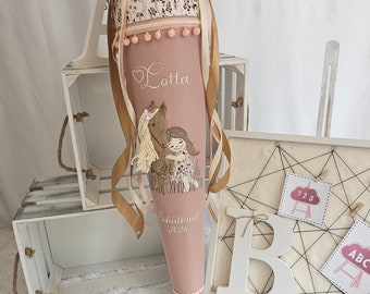 May include: A pink school cone with a floral fabric top and gold ribbons. The cone features an embroidered illustration of a girl and a horse, with the name "Lotta" and the text "Schulkind 2024".