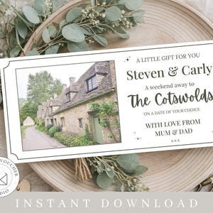 以下が含まれることがあります： 石造りの村の写真と「A LITTLE GIFT FOR YOU Steven & Carly A weekend away to The Cotswolds」のテキストが入った白いギフト券。 ギフト券は、緑と木のトレイで囲まれています。
