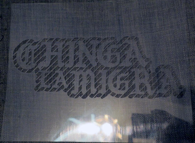 Puede incluir: Un est&eacute;ncil transparente con las palabras "CHINGA A TU MADRE" en una fuente audaz y estilizada. El texto est&aacute; recortado, revelando el fondo. El est&eacute;ncil se utiliza probablemente para proyectos de artesan&iacute;a o dise&ntilde;o.