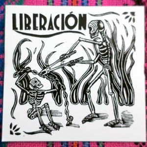 May include: Black and white sticker featuring the word "LIBERACION" above a skeletal figure breaking chains held by another skeleton. The artwork has a Day of the Dead theme.