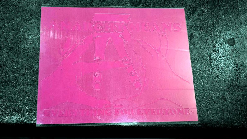 May include: A pink, rectangular sticker with the words "WATCHING JEANS" and "LIVE OFFERING FOR EVERYONE" etched into the surface. The design features a stylized illustration of a person wearing jeans.