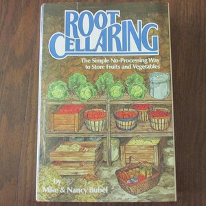 May include: A book cover titled "Root Cellaring" with blue and white text. The cover depicts a rustic scene of a root cellar with shelves of produce, including cabbages, tomatoes, and baskets of vegetables. The authors are Mike & Nancy Bubel.