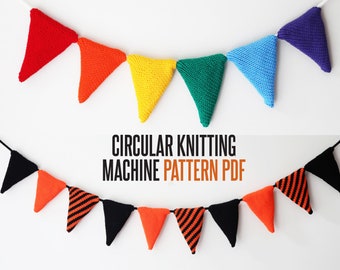 Op de afbeelding: Een kleurrijke gebreide vlaggenlijn met afwisselend rode, oranje, gele, groene, blauwe en paarse driehoekige vlaggen. De vlaggenlijn hangt aan een witte achtergrond. De tekst "CIRCULAR KNITTING MACHINE PATTERN PDF" staat onder de vlaggenlijn.