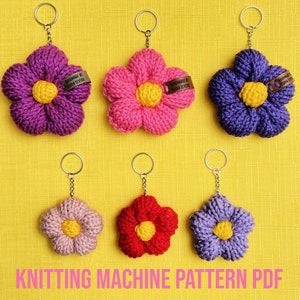 May include: Six crocheted flower keychains in pink, purple, and red with yellow centers. The keychains are handmade and have a tag that says "Handmade by Donna Leyba".