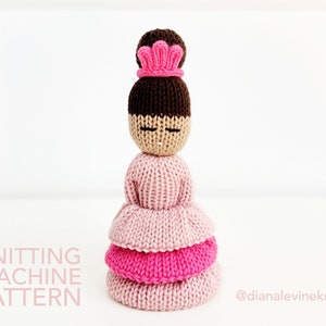 May include: Knitting machine pattern for a pink and brown doll with a pink crown. The doll has a tiered skirt and closed eyes. The text "KNITTING MACHINE PATTERN" is at the bottom left of the image. The text "@dianalevineknits" is at the bottom right of the image.