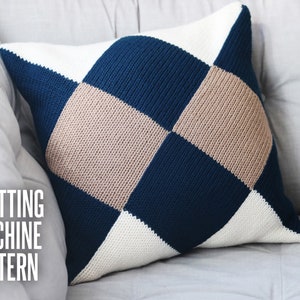 May include: A knitted pillow with a diamond pattern in shades of blue, beige, and white. The pillow is on a gray couch. "Knitting Machine Pattern" is written in black text on the couch.
