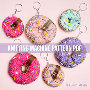 Op de afbeelding: Breipatroon voor breimachine om donutvormige sleutelhangers te maken. De afbeelding toont vijf gehaakte donuts in verschillende kleuren, waaronder roze, paars en blauw, met witte en gele sprinkles. Elke donut heeft een bruin leren label met de tekst "Handmade by Diana Levine".