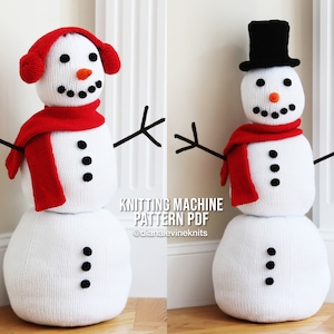 May include: Two knitted snowmen with red scarves and black buttons. The snowman on the left has a red hat with ear flaps. The snowman on the right has a black top hat.  Knitting Machine Pattern PDF @dianalevineknits