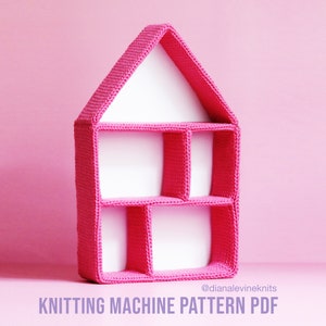 May include: A pink, house-shaped shelf with several compartments. The shelf is made of a knitted material and has a white interior. The text "KNITTING MACHINE PATTERN PDF" is displayed at the bottom of the image.
