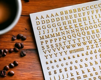 May include: A white sheet with gold letters of the alphabet, A through Z, in a repeating pattern. The letters are arranged in rows and columns. The sheet is labeled "MYSW002".