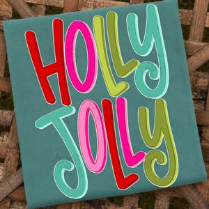 Op de afbeelding: Een blauwgroen T-shirt met de tekst HOLLY JOLLY in een speels, afgerond lettertype. De letters zijn gekleurd in levendige tinten rood, felroze, limoengroen en turquoise, elk omlijnd met een subtiele witte rand voor een gelaagd effect.
