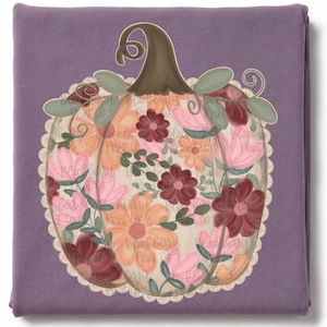 May include: A folded purple fabric featuring a central pumpkin graphic. The pumpkin is filled with a floral pattern of pink, orange, and dark red flowers, green leaves, and vines. A cream-colored scalloped lace border surrounds the pumpkin.