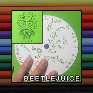Peut inclure: Un pochoir de dessin circulaire blanc avec des découpes numérotées pour créer un personnage de dessin animé, incluant un encart vert montrant l'illustration terminée de Beetlejuice, avec le texte BEETLEJUICE imprimé en blanc en bas.