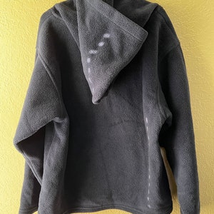 May include: A dark grey fleece hoodie with a hood. The hoodie has a zip fastening and a kangaroo pocket.