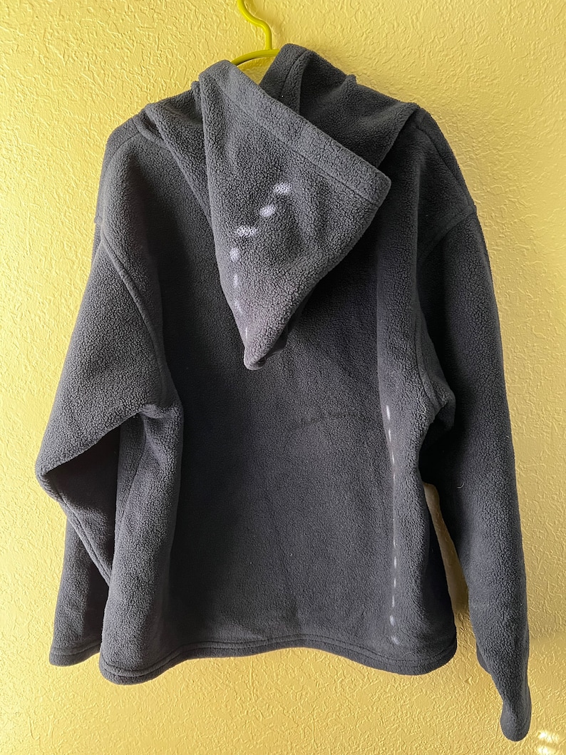 May include: A dark grey fleece hoodie with a hood. The hoodie has a zip fastening and a kangaroo pocket.