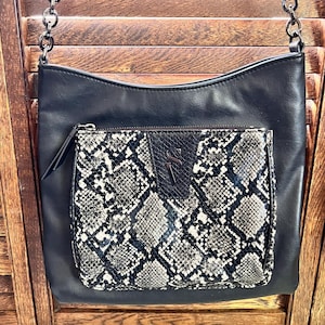 May include: A black leather shoulder bag with a snakeskin patterned flap pocket and a silver chain strap.