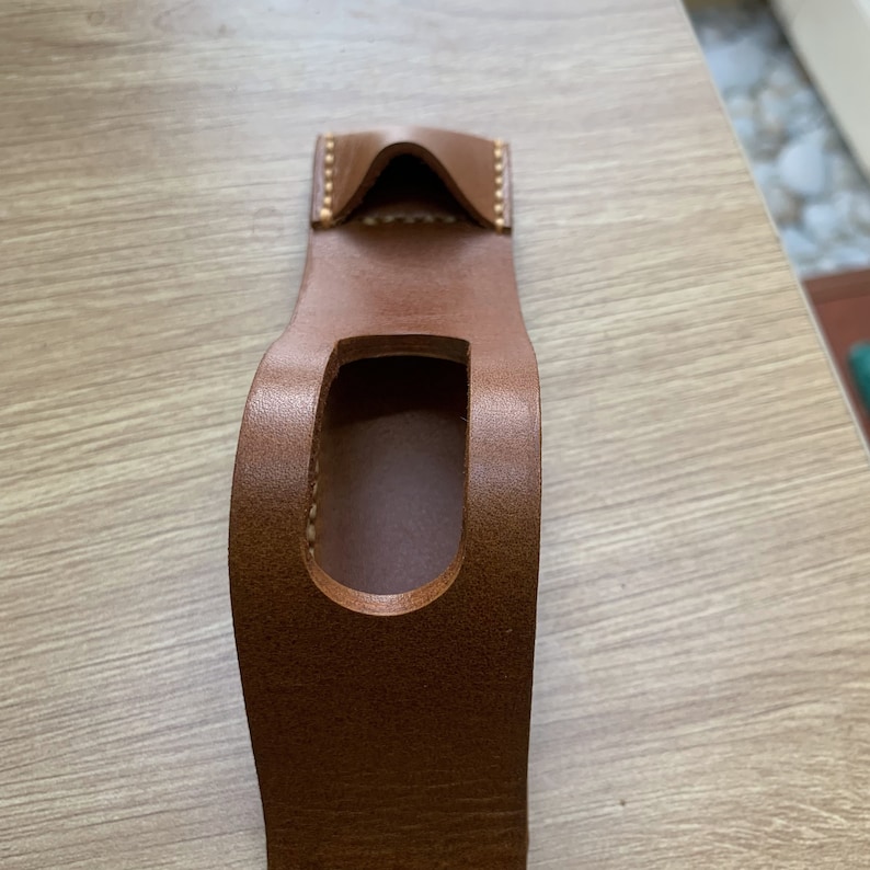 May include: A brown leather phone case with a cut-out for the phone's camera lens.