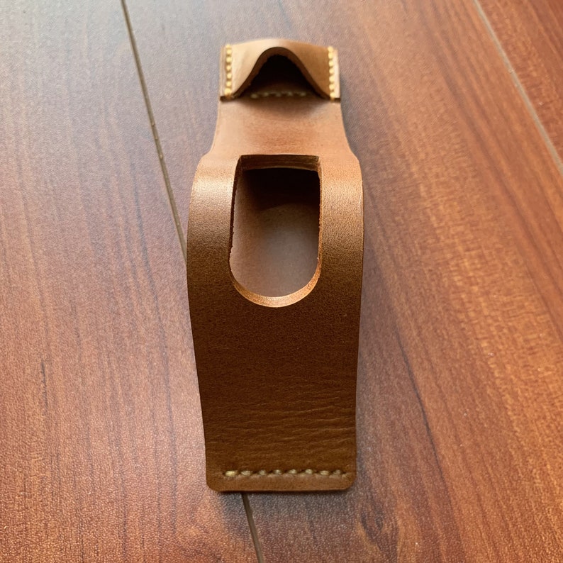 May include: A brown leather phone case with a cutout for the camera lens.