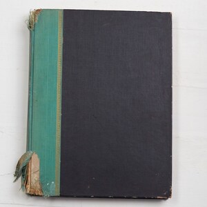 May include: A black hardcover book with a teal spine and gold accents. The book is slightly worn and has a few tears on the spine.