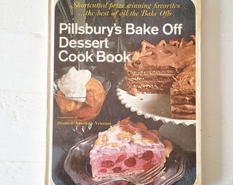 May include: A vintage Pillsbury's Bake Off Dessert Cook Book with a brown cover featuring a chocolate cake and a cherry pie. The book is a compilation of prize-winning recipes from the Pillsbury Bake Off contest.