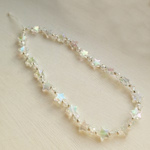 May include: A delicate iridescent star-shaped bead necklace with a silver thread.