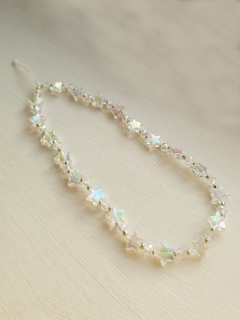 May include: A delicate iridescent star-shaped bead necklace with a silver thread.