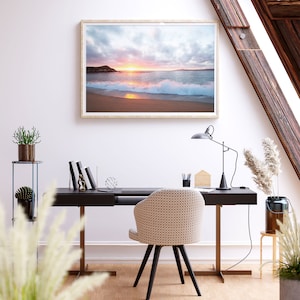 Peut inclure: Une photographie encadr&eacute;e d'une sc&egrave;ne de plage avec un coucher de soleil sur l'oc&eacute;an. La photo est accroch&eacute;e &agrave; un mur blanc au-dessus d'un bureau noir avec une chaise blanche. Il y a des plantes sur une &eacute;tag&egrave;re &agrave; gauche du bureau.