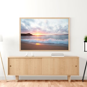 Peut inclure: Une photographie encadr&eacute;e d'une sc&egrave;ne de plage avec un coucher de soleil sur l'oc&eacute;an. La photo montre une plage de sable avec des vagues qui se brisent sur le rivage. Le ciel est un m&eacute;lange de rose, d'orange et de violet.