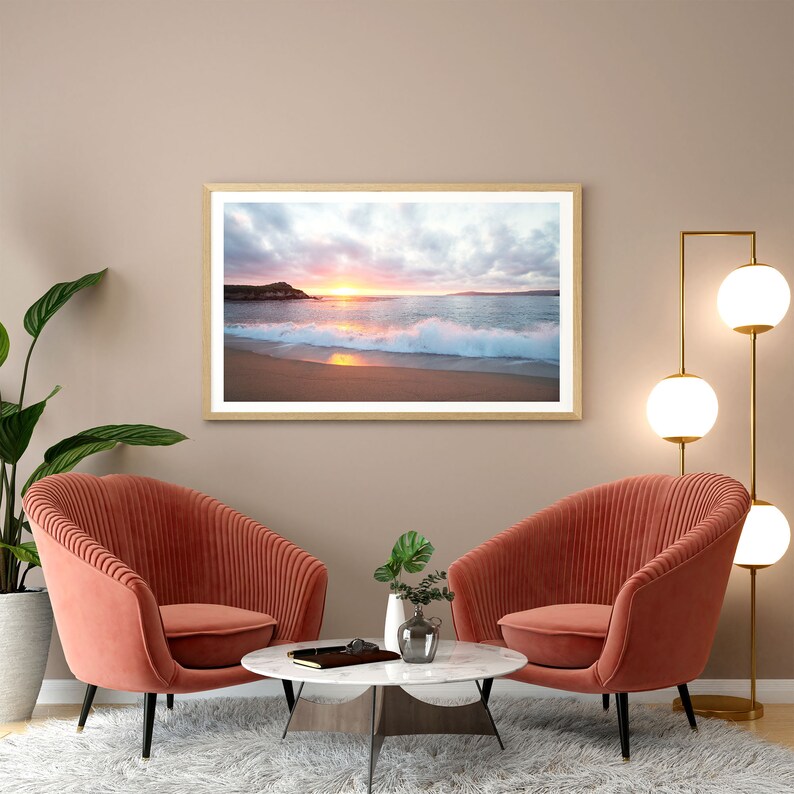 Peut inclure: Deux fauteuils corail avec une table basse en marbre blanc devant eux. Une photographie encadr&eacute;e d'une sc&egrave;ne de plage avec un coucher de soleil est accroch&eacute;e au mur derri&egrave;re les fauteuils. Un lampadaire dor&eacute; avec des abat-jours blancs en globe se trouve dans le coin de la pi&egrave;ce.