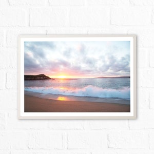 Peut inclure: Une photographie d'une sc&egrave;ne de plage avec un coucher de soleil sur l'oc&eacute;an. Les vagues se brisent sur le rivage et le ciel est un m&eacute;lange de rose, d'orange et de violet.