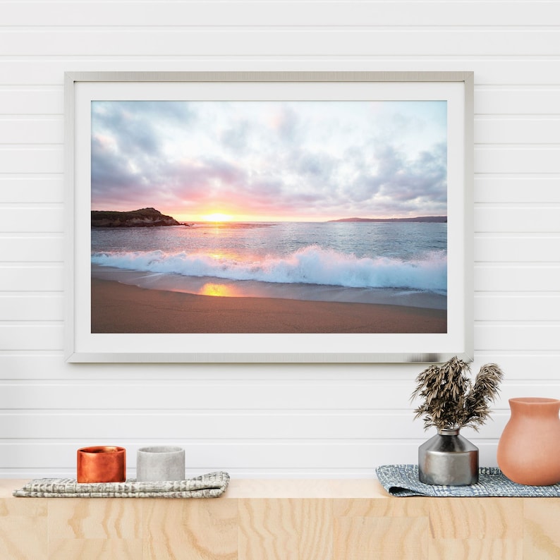 Peut inclure: Une photographie encadr&eacute;e d'une sc&egrave;ne de plage avec un coucher de soleil sur l'oc&eacute;an. La photo montre une plage de sable avec des vagues qui se brisent sur le rivage. Le ciel est un m&eacute;lange de rose, d'orange et de violet.