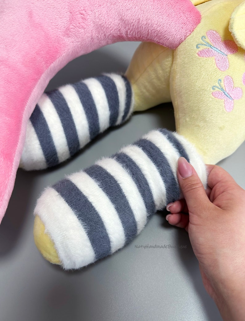 May include: A yellow plush toy with pink butterfly embroidery and gray and white striped legs. The toy is shaped like a horse with a pink head and neck.