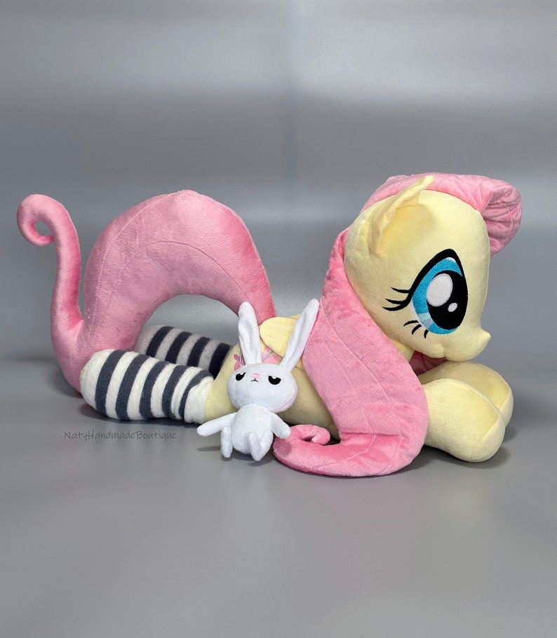 May include: Pink and yellow plush toy pony with a white and gray striped sock on one leg and a white plush bunny with black eyes. The pony has a pink mane and tail.