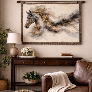 May include: A woven wall tapestry featuring a watercolor painting of a horse's head and flowing mane in shades of gray, black, and gold. The tapestry is framed with a dark brown rod and fringe. The tapestry hangs above a dark wood console table.