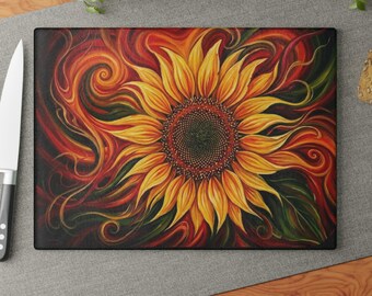 Peut inclure: Planche à découper rectangulaire avec un motif de tournesol vibrant. Le tournesol a des pétales jaunes et un centre brun foncé, sur un fond de tourbillons rouges, oranges et verts. La planche est probablement en verre ou en matériau similaire.