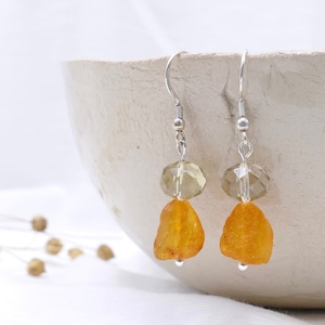 Puede incluir: Un par de pendientes colgantes de plata con cuentas de ámbar y vidrio facetado transparente. Los pendientes tienen un diseño sencillo y son perfectos para el uso diario.