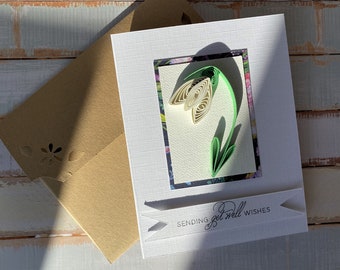 May include: A white card with a green and white paper flower and the text "Sending get well wishes".