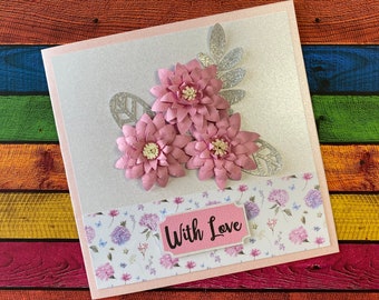 May include: A white card with a pink and silver floral design. The card has a pink banner with the text "With Love" on it.