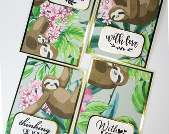 May include: Four greeting cards with a sloth design. Each card has a different message: "Thankful for you", "With love", "Thinking of you", and "With love". The cards are decorated with a tropical leaf pattern and pink flowers.