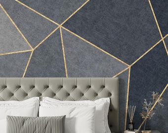 May include: A bedroom scene featuring a gray tufted headboard, white pillows, and a striped accent pillow. The wall behind the bed is a dark blue with gold geometric lines. A nightstand with a diffuser and decorative items is visible.