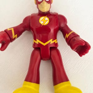 May include: A red and yellow Flash action figure. The figure has a red body with yellow lightning bolt accents and yellow boots. The Flash logo is on the chest. The figure has a yellow mask and a red helmet.