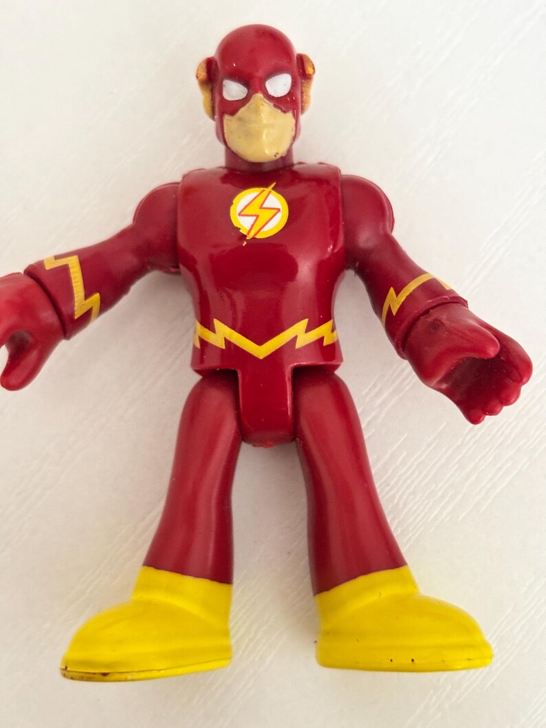 May include: A red and yellow Flash action figure. The figure has a red body with yellow lightning bolt accents and yellow boots. The Flash logo is on the chest. The figure has a yellow mask and a red helmet.