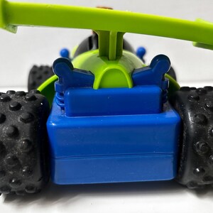 以下が含まれることがあります： 鮮やかな配色が特徴的なおもちゃの車のクローズアップ。車体は青色、スポイラーは緑色、タイヤは黒色です。タイヤはテクスチャ加工が施されています。スポーティーなデザインの車です。