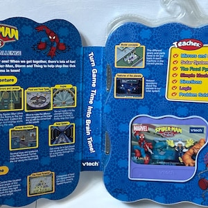 May include: A VTech Spider-Man and Friends Doc Ock's Challenge educational video game cartridge and packaging. The blue cardboard display features game instructions, learning objectives like mirrors, lenses, and the solar system, and Marvel character graphics.