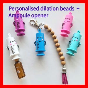 May include: A collection of colorful, syringe-shaped items, including pink, blue, purple, and white, with smiling faces and measurement markings. The image also includes a wooden bead strand and an ampoule opener.
