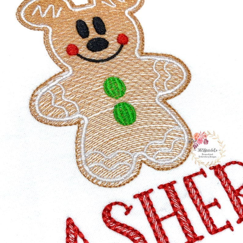 May include: Embroidered design of a gingerbread man with red cheeks, green buttons, and a smiling face. The text "ASHER" is embroidered in red below the gingerbread man.