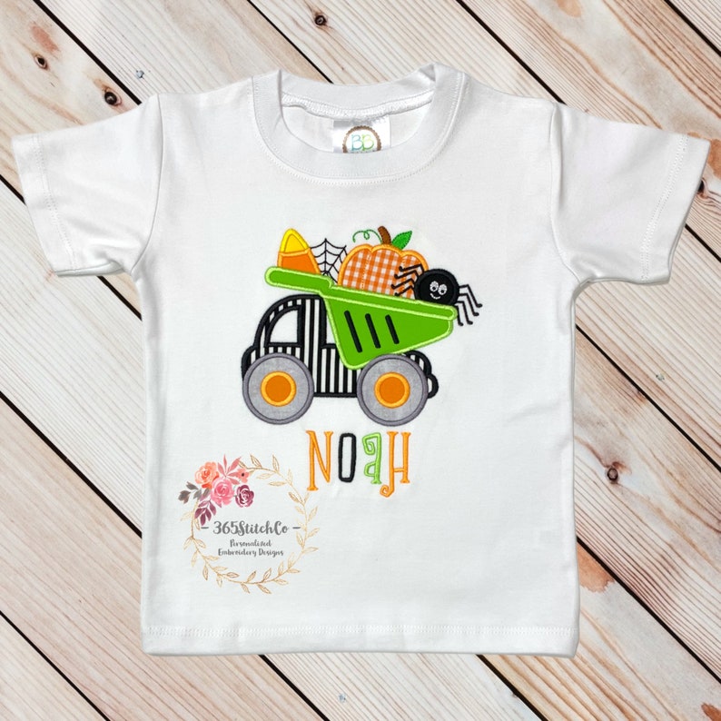 Puede incluir: Camiseta blanca de manga corta con un cami&oacute;n volquete verde y negro que lleva una calabaza, una ara&ntilde;a y ma&iacute;z dulce. El nombre "NOAH" est&aacute; bordado debajo del cami&oacute;n.